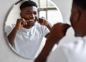 Man in white shirt flossing his teeth