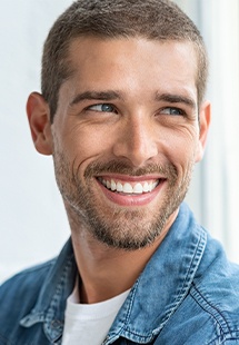 Man in denim jacket looking to side and smiling