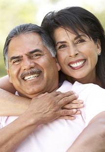 Senior woman hugging senior man from behind