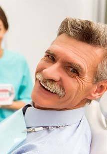 Senior man sitting back in dental chair and smiling