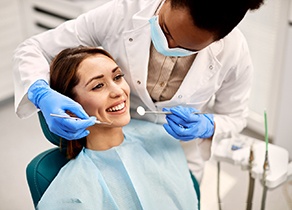 Dentist using tools to look at smiling patient's teeth