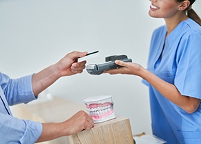 Smiling receptionist taking credit card payment from patient